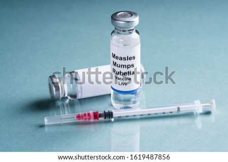 Measles Mumps Rubella Vaccine Vials With Syringe Over Turquoise Background Royalty-Free Stock Photo #1619487856