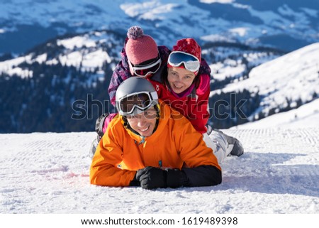 Portrait Of A Happy Family Lying Stacked On Top Of Each Other In Snow