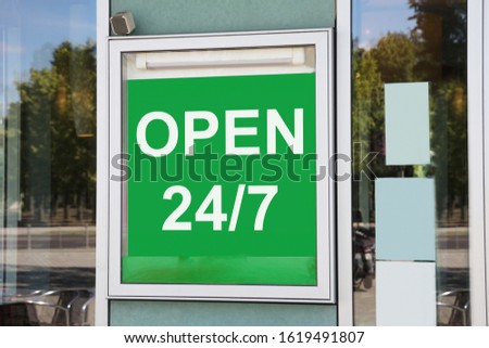 Close-up Of Green Open 24/7 Information Board Hanging On Glass Door