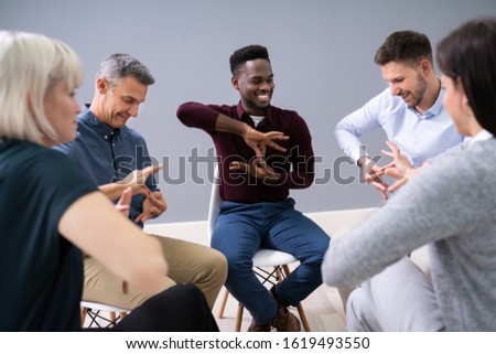 Close-up Of A Person Teaching Sign Languages To Multiethnic Pupils Sitting On Sofa At Home