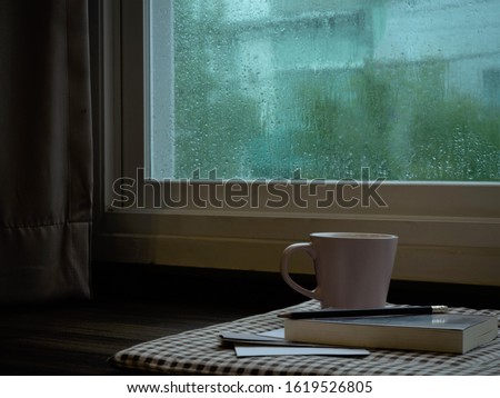 a cup coffee and book  on rainy day window background