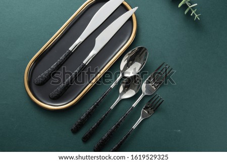 Chopsticks, spoons, knives and forks are arranged on ceramic plates