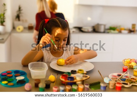 little girl having fun to paint easter eggs