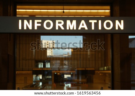 illuminated information sign against the backdrop of reflections of residential buildings