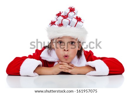Boy thinking of his christmas presents - wearing a santa hat full of tiny gift boxes