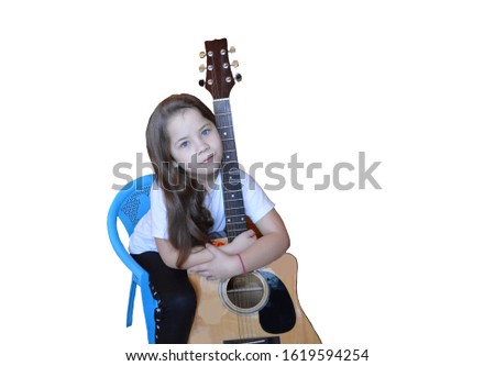 a little girl with long hair on a white isolated background is learning and playing a musical instrument guitar at home