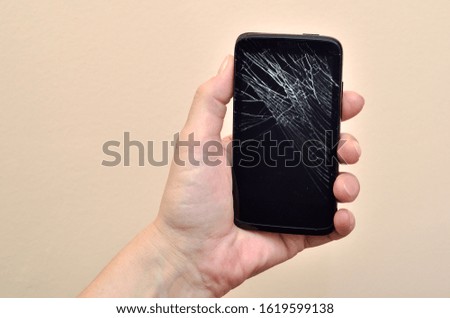 Hand of a woman holding a broken smartphone. Close-up.