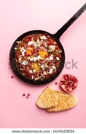 breakfast shakshuka eggs served in a pan with bread and on a color background