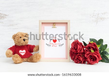 Mockup Picture frame and cute bear with Bouquet of red roses on grunge white wood. Valentines Day Background concept with copy space. Mock up with photo frame for your picture or text