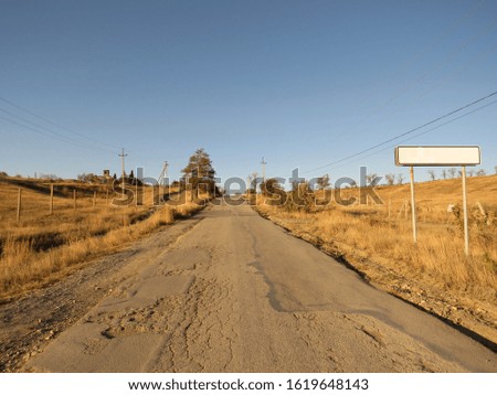 Picture of village life. Old broken asphalt road on the background of hilly landscape