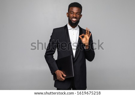 Serious African American businessman holding laptop computer on white background