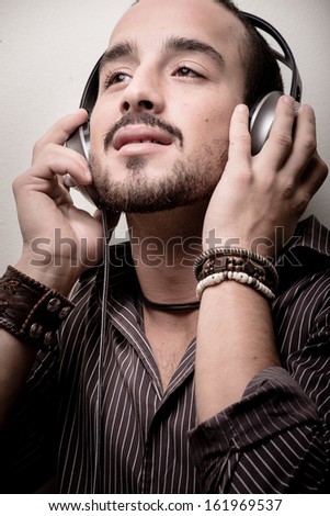 young stylish man listening to music on gray background