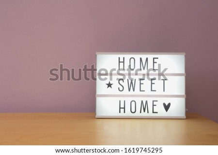 'Home sweet home' text in lighbox on wooden shelf, modern retro decoration purple wall