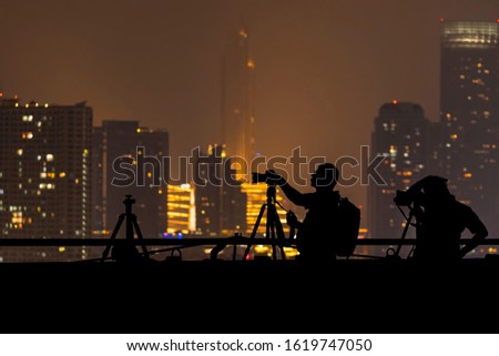 Silhouettes of mens taking a photo with blurred buildings background
