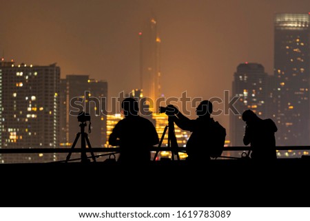 Silhouettes of mens taking a photo with Bangkok Air Pollution PM 2.5 cover on the buildings background
