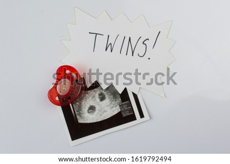 Twins ultrasound picture and a red soother. 