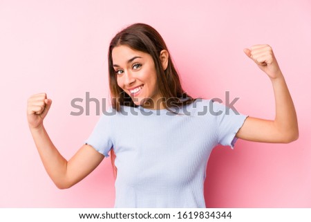 Young caucasian woman wearing a ski clothes isolated showing strength gesture with arms, symbol of feminine power