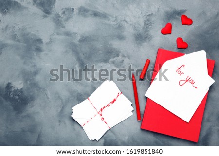 Paper envelopes with hearts, notepad and text For You on grey background