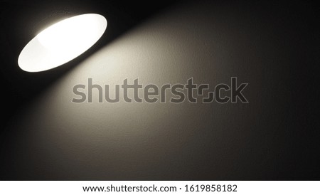 Desk lamp shining warm light in the dark room on the wall with copy space for add text. Living, home and office interior concept
