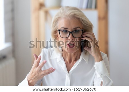 Outraged mature businesswoman talking by phone arguing with client feels irritated, 60s employee disputing having unpleasant conversation with customer, business problem solution, bad service concept Royalty-Free Stock Photo #1619862670