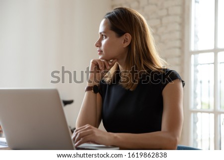 Thoughtful businesswoman looking in distance, using laptop, pensive confident female employee executive pondering startup ideas, developing business strategy, dreaming or visualizing at workplace