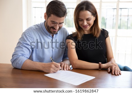 Happy married couple satisfied clients signing contract, making legal deal, smiling husband putting signature on documents, family purchasing real estate, new house, taking loan or mortgage Royalty-Free Stock Photo #1619862847