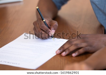 Close up African American man signing contract, job agreement, male client putting signature on legal documents, taking loan or mortgage, purchase real estate, insurance or investment deal