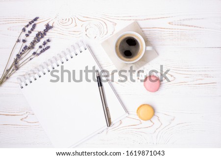 Composition from blank diary, cup of coffee and macaroon and lavender flowers on a white shabby wooden table. Fashion flat lay.