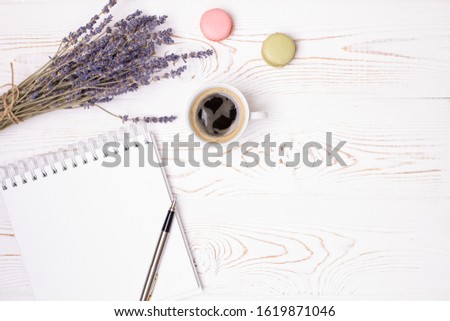 Composition from blank diary, cup of coffee and macaroon and lavender flowers on a white shabby wooden table. Fashion flat lay.