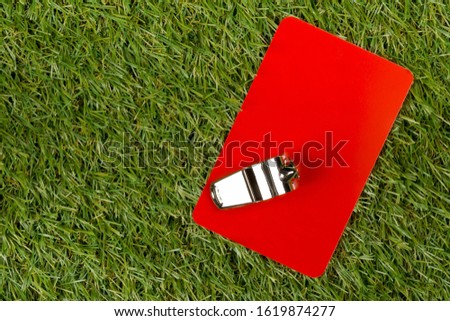 Soccer sports referee red card with chrome whistle on grass background - penalty, foul or sports concept, top view flat lay from above