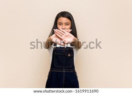Young cute chinese teenager Young blonde woman wearing a coat against a pink background doing a denial gesture