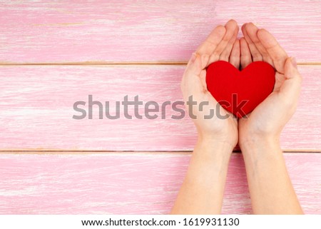 Woman Hands Holding Red Heart on Pink Wooden Background. Concept of Health care, Love, Donation, Family Insurance, Happy Valentines Day. Top View, Copy Space