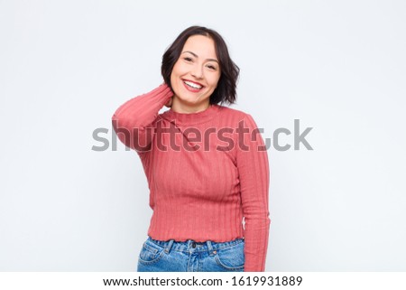young pretty woman laughing cheerfully and confidently with a casual, happy, friendly smile against white wall
