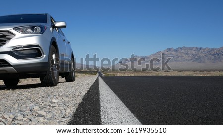 Car on side of the road in the Death Valley - sunny day seen from the road bottom - the road stretching over a horizon Royalty-Free Stock Photo #1619935510