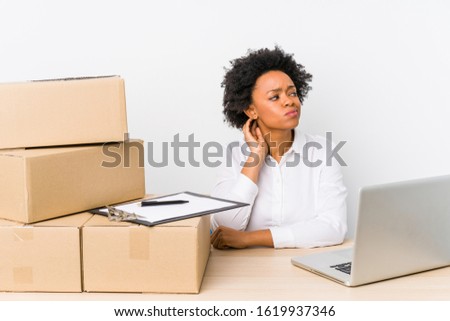 Warehouse manager sitting checking deliveries with laptop touching back of head, thinking and making a choice.