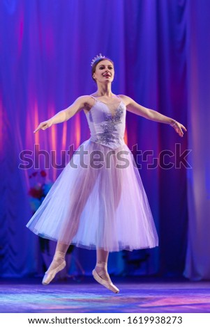 Young girl ballerina in a white tutu dancing performance on stage in a theater on a blue background