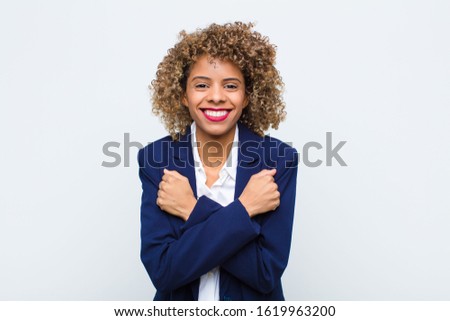 young woman african american smiling cheerfully and celebrating, with fists clenched and arms crossed, feeling happy and positive against flat wall