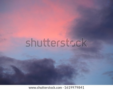 Dark gray and red clouds on a blue sky background