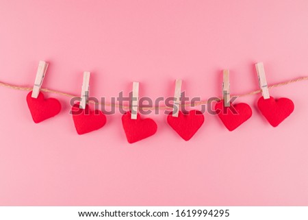 Red heart shape decoration hanging on line with copy space for text on pink background. Love, Wedding, Romantic and Happy Valentine day holiday concept