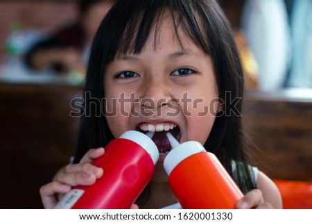 Asian children holding tomato sauce & Ketchup bottle in restaurant