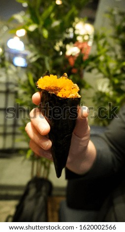 hands holding california roll in Sushi Restaurant                     