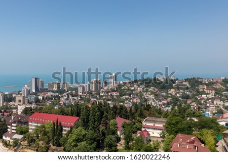Blue coast of Black Sea in Sochi with houses and mountains, aerial panoramic view.