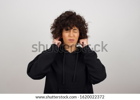 Stop making this annoying sound! Headshot of unhappy stressed out young female making worry face, plugging ears with fingers, irritated with loud noise coming from neighbours who live above her.