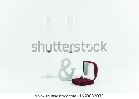 Marriage proposal and love concept for Valentine`s day, box with wedding or engagement ring with brilliant. Glass of champagne on white background