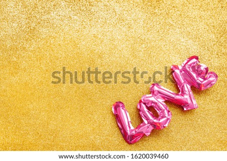 Valentines Day creative concept. Inflatable pink glossy foil balloon shaped word Love golden background. Top view flat lay with copy space. Holiday, celebration, wedding bachelorette party decoration