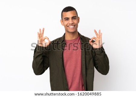 Young African American man over isolated white background showing an ok sign with fingers