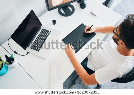 Overhead view of photographer editing pictures on tablet in home office