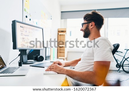 Young photographer working in home office editing and choosing pictures