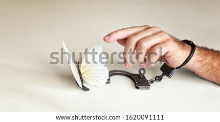 Conceptual picture of the separation or divorce of spouses or lovers. Background, banner with open handcuffs and a flying butterfly. The criminal is released from prison.