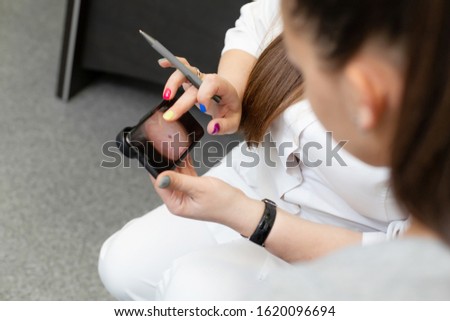 Young girl at a consultation with a dermatologist. Doctor shows pictures on a dermatoscope.